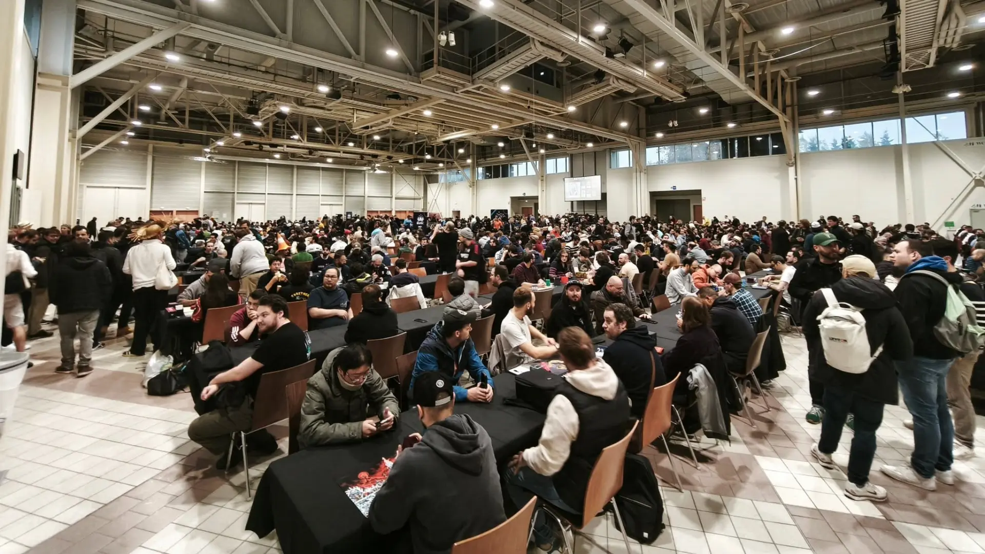 A convention hall full of players at trading card game tables